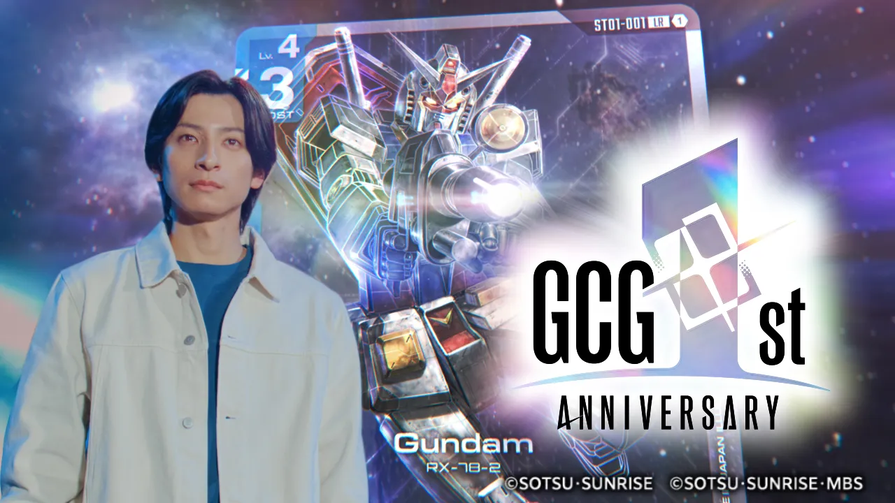 Gundam Card Game first anniversary key visual: a dark-haired man in a cream jacket standing in front of an oversized ST01-001 Gundam card showing the RX-78-2, beside a holographic GCG 1st Anniversary logo.