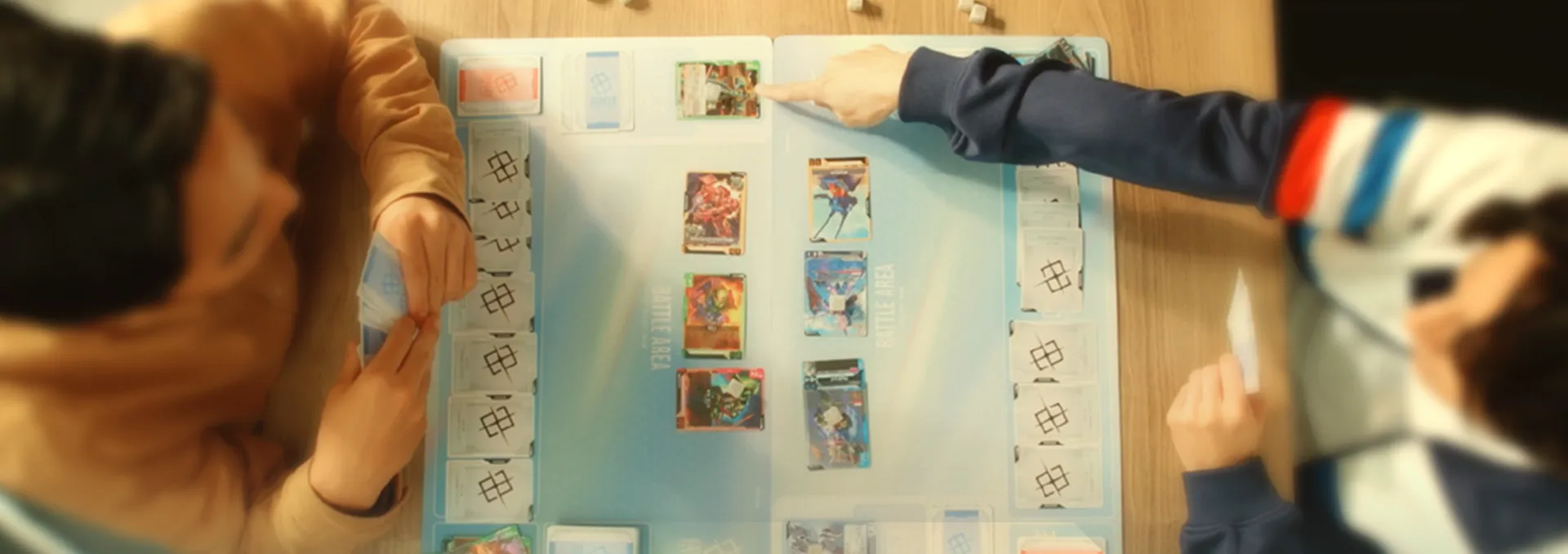 Two players mid-game on the official Gundam Card Game playmat, with rows of face-down shields down each outer edge and Unit cards deployed in the battle areas.
