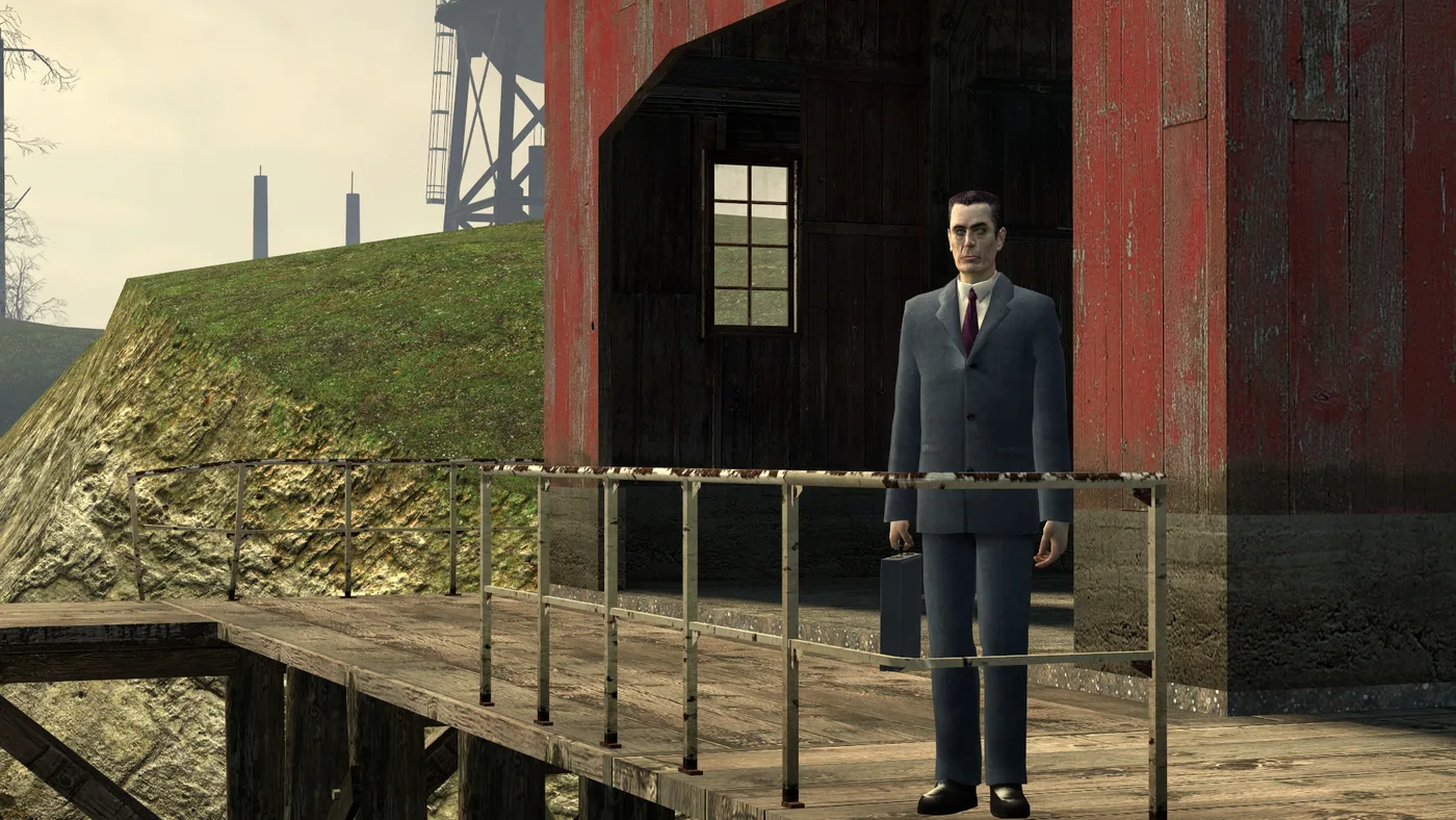 The G-Man, briefcase in hand, standing at the railing of Station 7's wooden walkway in front of a weathered red barn, a steel tower and smokestacks on the hazy skyline behind him, in Half-Life 2's Water Hazard chapter.