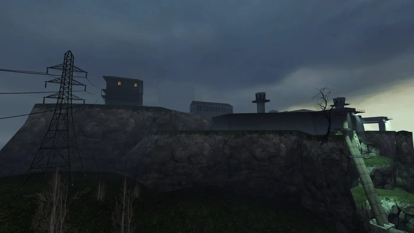 Nova Prospekt seen from the coast road below: a lit guard tower and long concrete blocks on a rock escarpment under a heavy dusk sky, with a power pylon and a concrete stairway in the foreground.