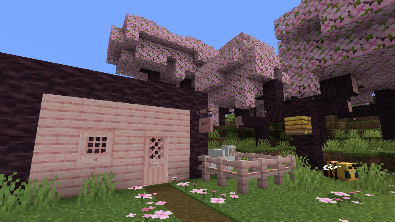 A Minecraft house and structures built from the salmon-pink cherry wood set in a cherry grove biome.