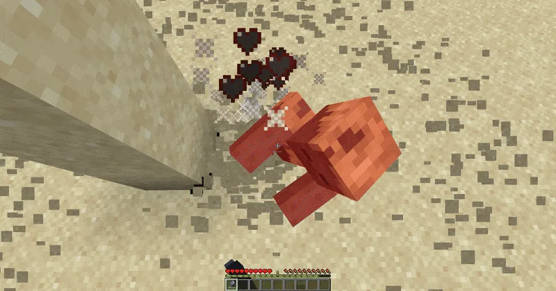 A Minecraft husk taking mace smash-attack damage in a desert, flashing red with critical-hit particles and floating damage hearts after a player fell onto it.