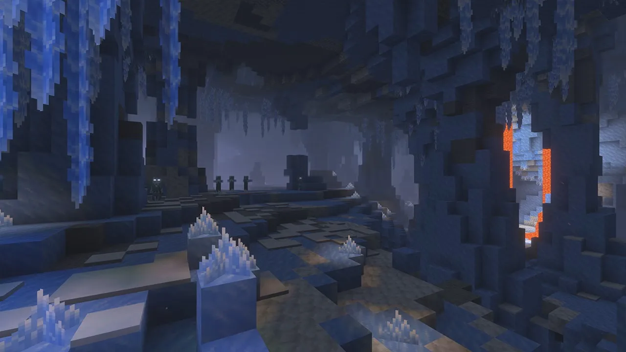 A Minecraft ice cave with walls of blue packed ice, long icicles hanging from the ceiling, pale ice crystal clusters on the floor, a few mobs standing in the dim distance and lava glowing through a gap in the wall on the right.