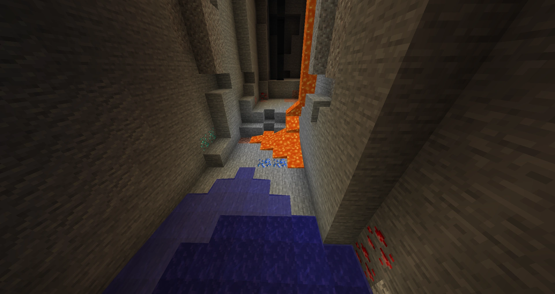 A deep cave with exposed deepslate, diamond, and redstone ore alongside lava and water — the kind of natural exposure that makes cave diving faster than blind tunneling, and a reminder of why a water bucket is mandatory.