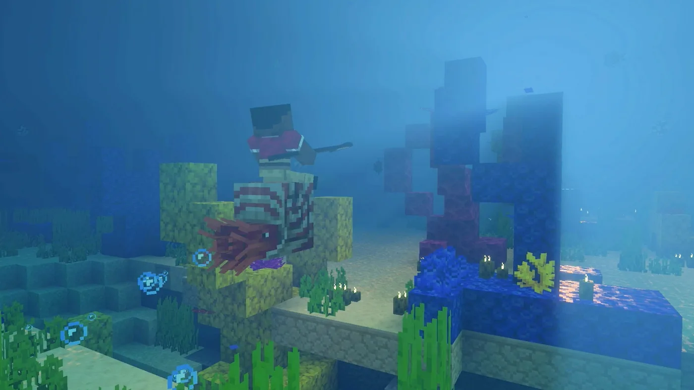 A Minecraft player riding a saddled nautilus underwater beside a coral reef of yellow, blue and red coral blocks, with seagrass, sea pickles and rising bubbles around them.
