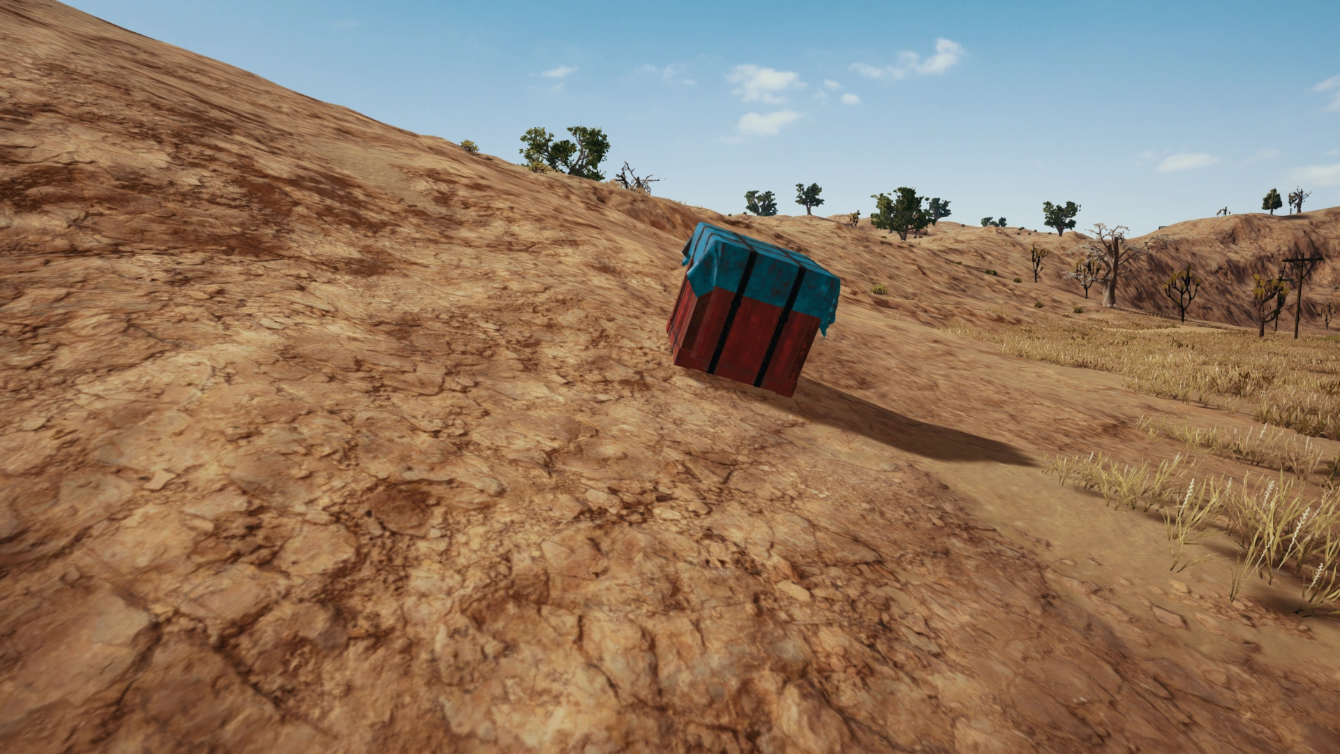A PUBG air drop crate on the ground marked by red smoke — the signal that a care package is open and ready to loot.